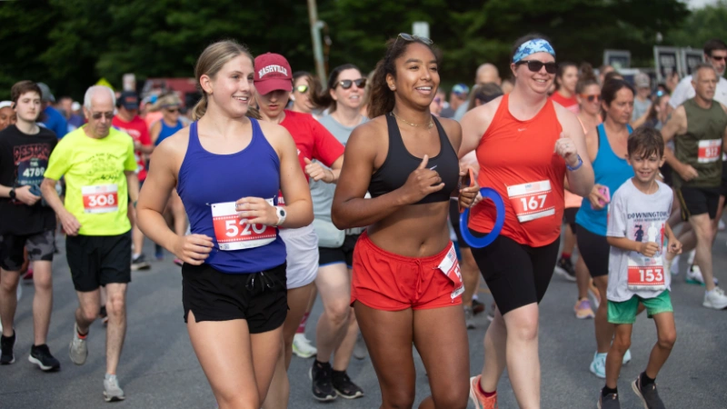 Two women running on Good Neighbor Day, surrounded by many other runners