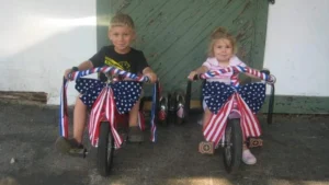 Two children atop decorated Big Wheels