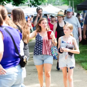 A woman and a young girl walk through the craft vendors area at Good Neighbor Day